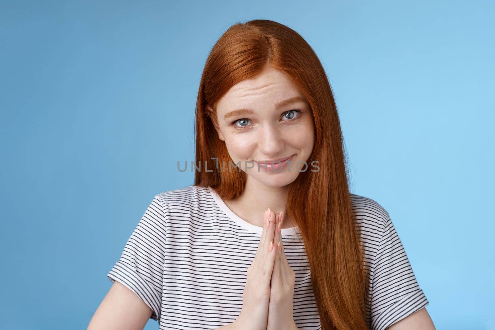 Cute girl acting kind angel gazing camera silly smiling asking please help press palms together pray glancing flirty begging favour standing blue background pleading sincere lend clothes. Lifestyle.