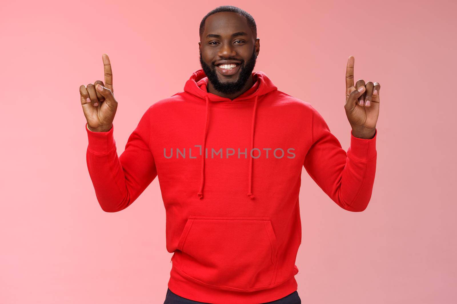 Devious cute african-american bearded guy in red hoodie smiling mysterious know exactly what you want pointing raised index fingers up grinning show perfect copy space promo, pink background by Benzoix