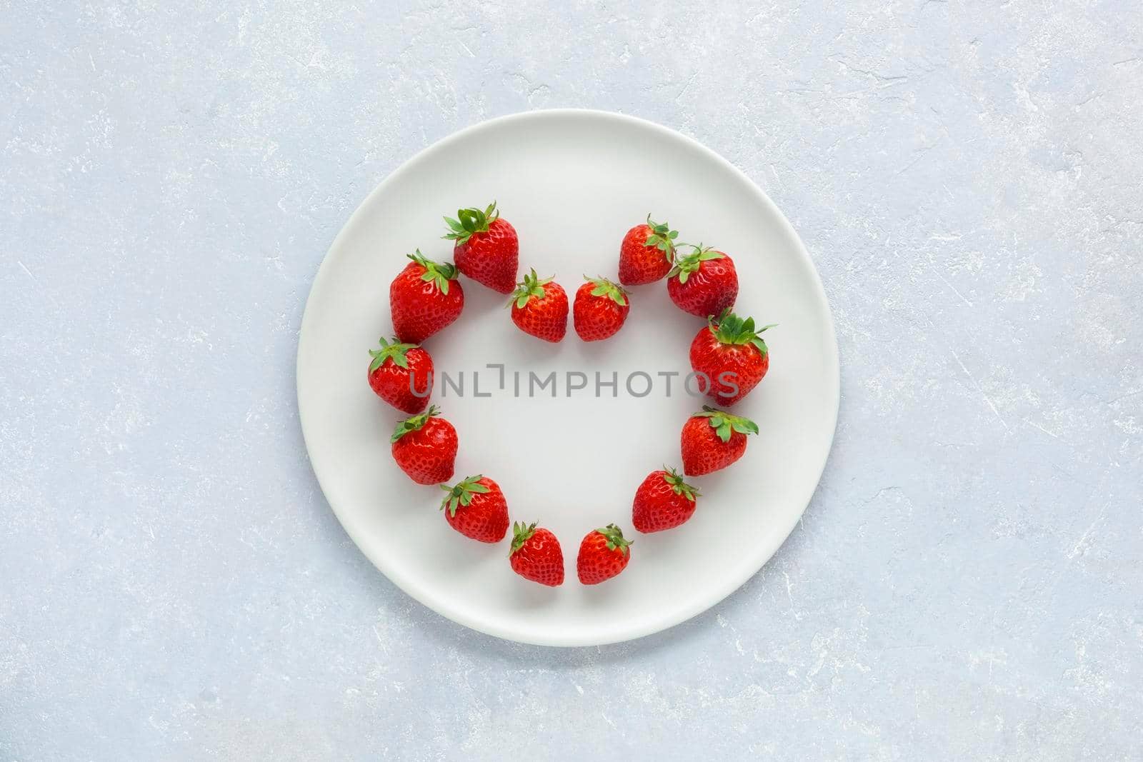 white plate with strawberries in a heart shape, concept of Valentine's Day, top view