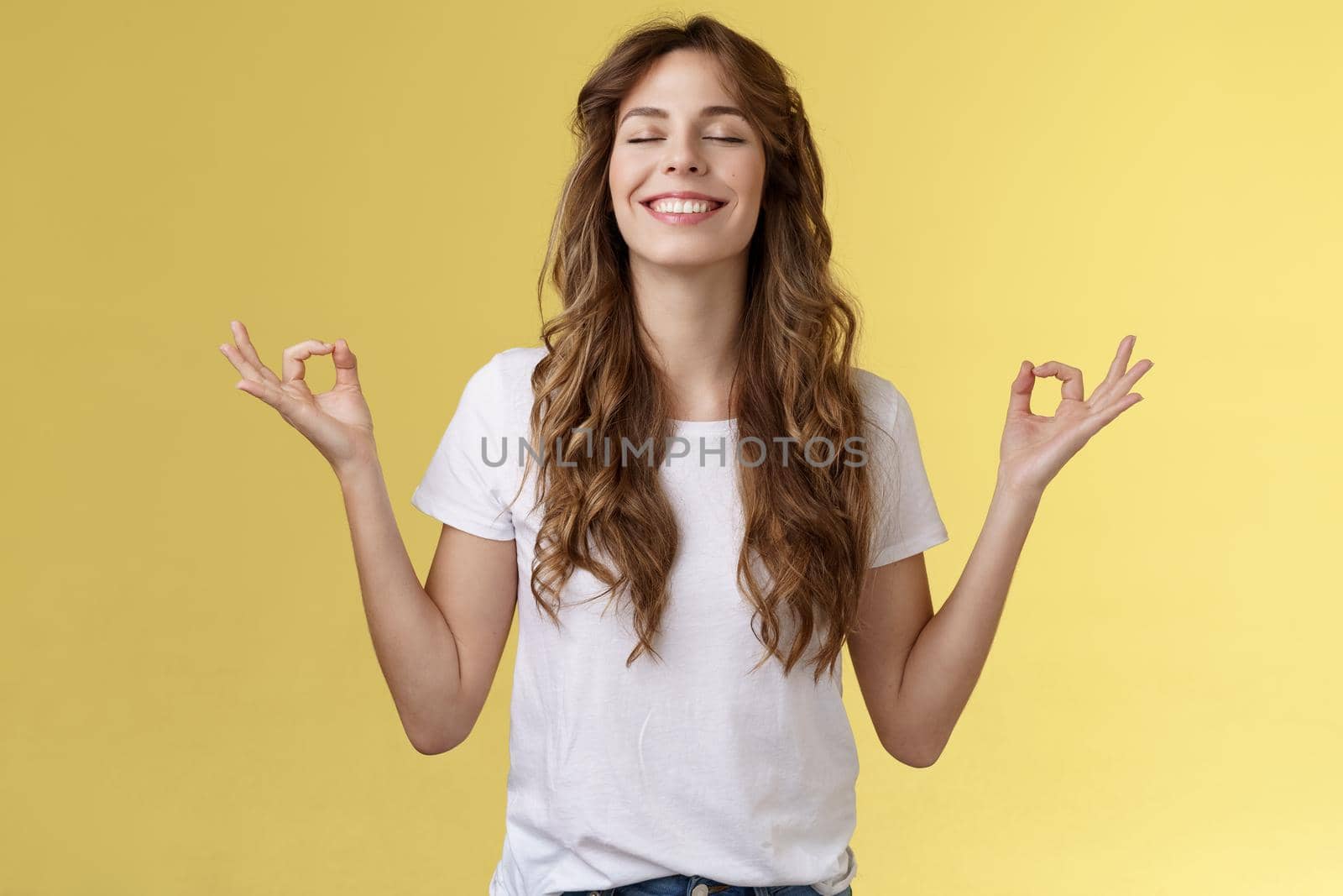 Patience, happiness, wellbeing. Cheerful relieved attractive peaceful relaxed young happy girl breathe inhale air smiling broadly close eyes lean sunlight meditating zen gesture hands sideways yoga by Benzoix