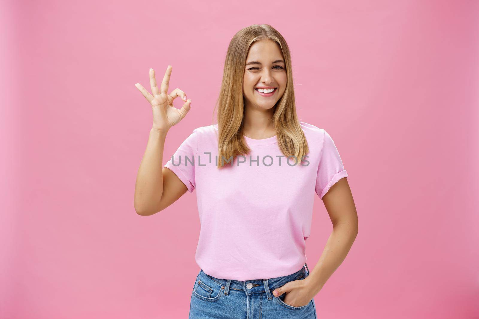You can count on me. Portrait of confident and assertive young female shop assistant assuring product is great smiling broadly winking at camera and showing okay gesture in like and approval. Body language concept