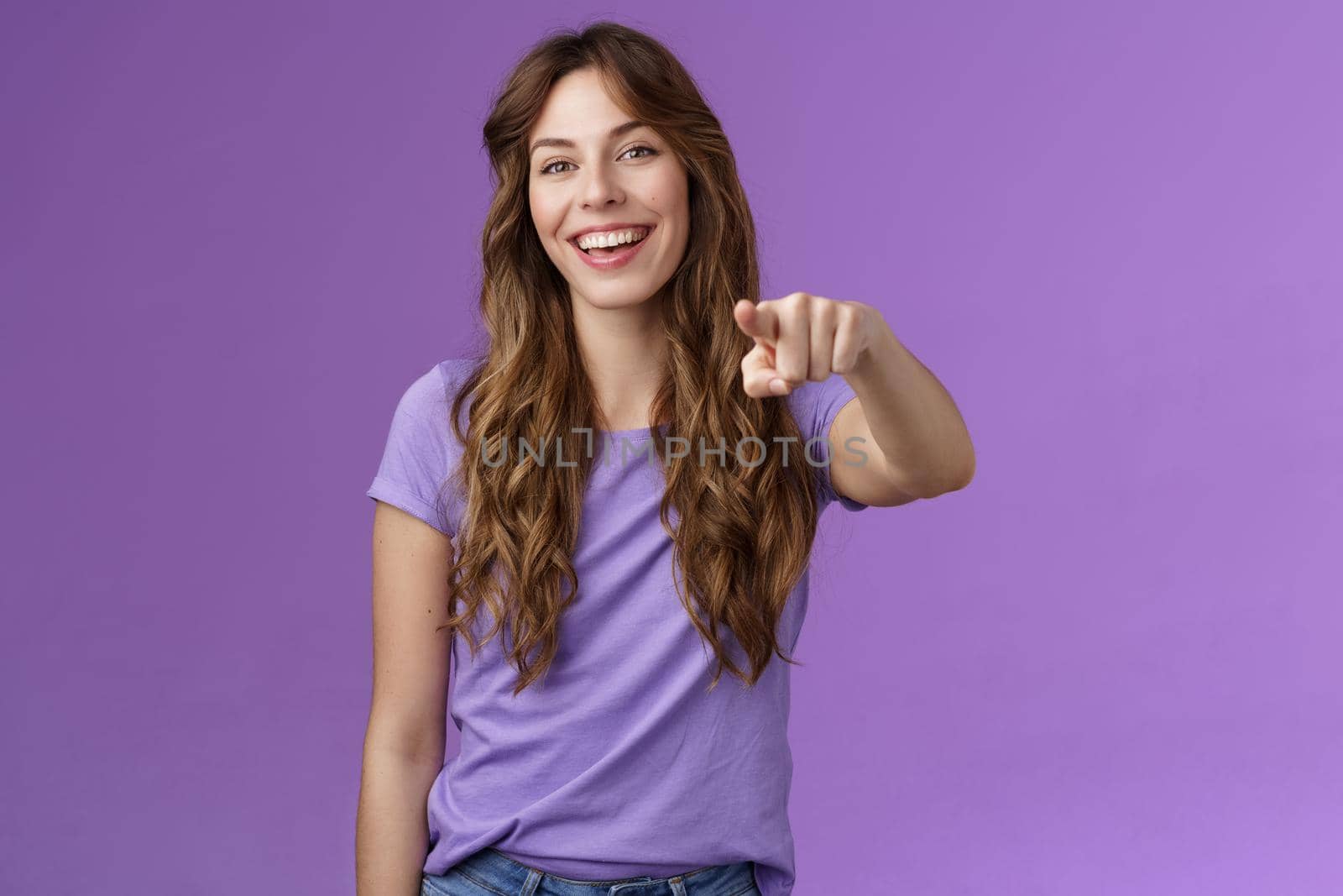 Entertained amused attractive lively girl curly hairstyle laughing happily pointing you finger indicate camera make choice smiling broadly assured believe decision right stand purple background.