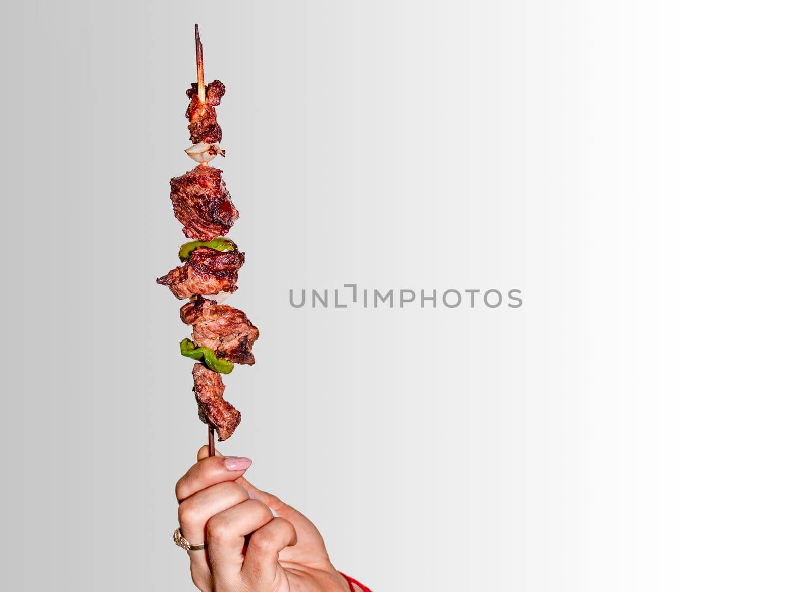 A hand holding a roast beef skewer, Hand holding roast beef skewer on white background