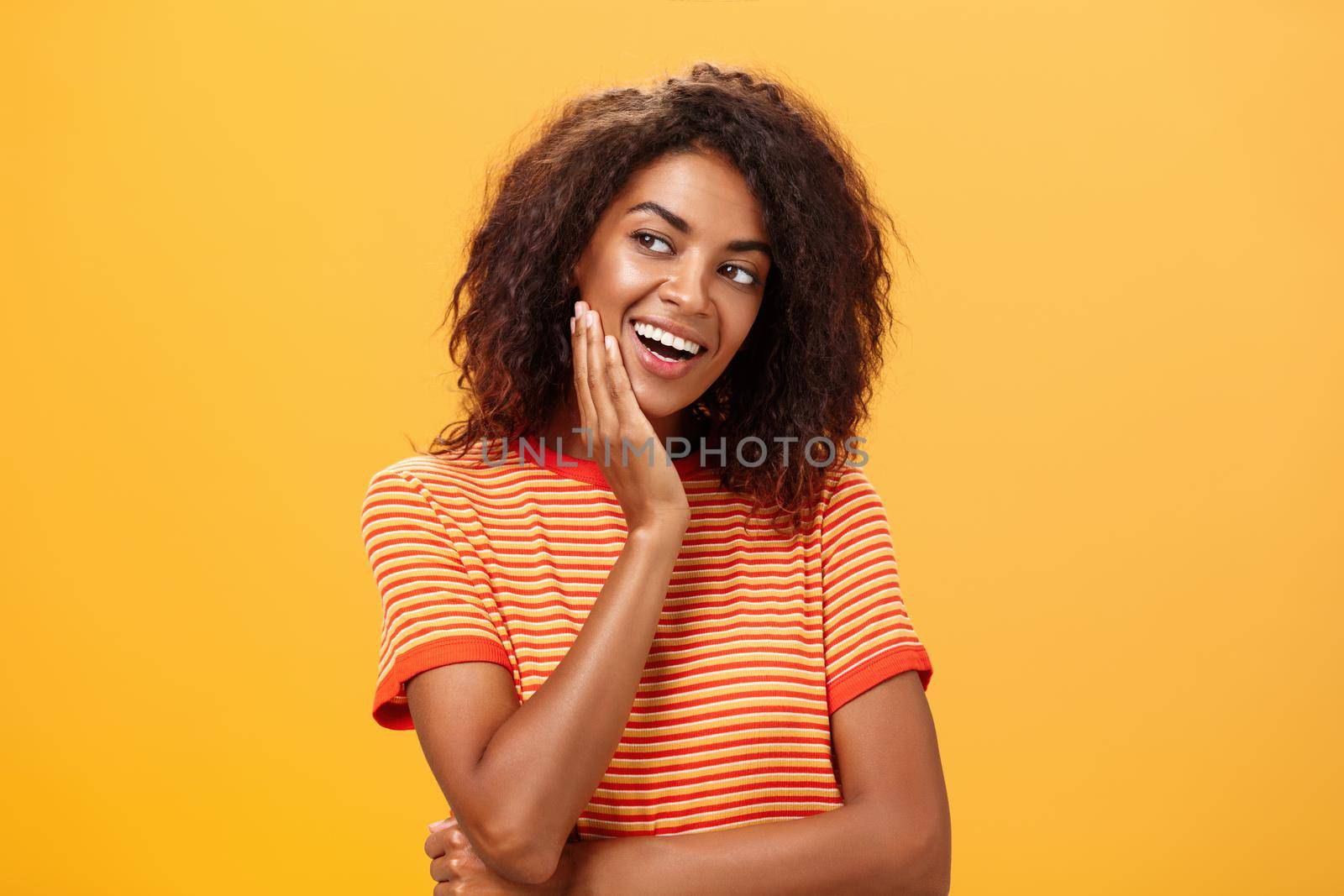 Cute creative and feminine stylish african american young female in striped t-shirt leaning head on palm gazing left with curious and adorable expression delightfully listening interesting story by Benzoix