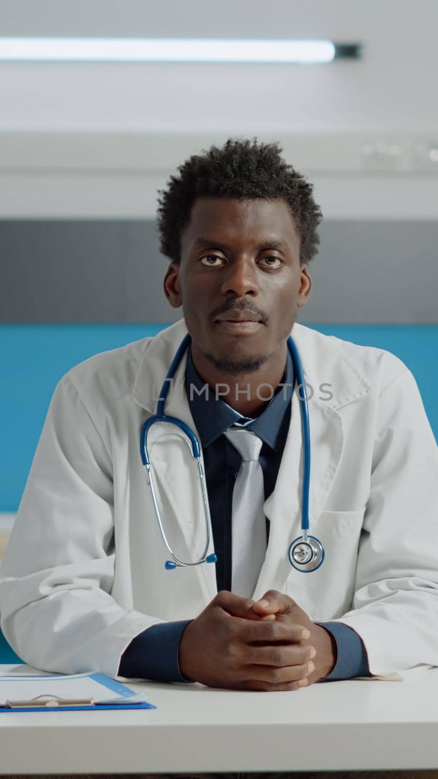 Young doctor talking on video call conference with patient for remote online consultation while sitting at desk in cabinet. Medic using internet communication for telemedicine treatment