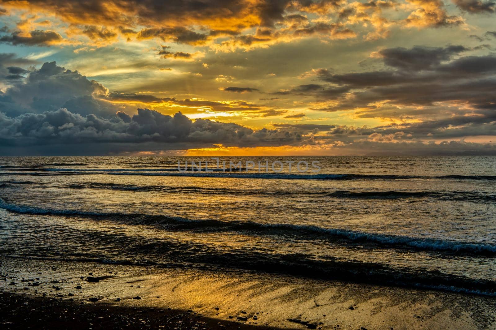 Evening view of the Pacific Coast of Tarcoles in Carara lit by the setting sun and glittering waves . Idyllic sunset landscape. Tarcoles, Costa Rica. Pura Vida concept, travel to exotic tropical country.