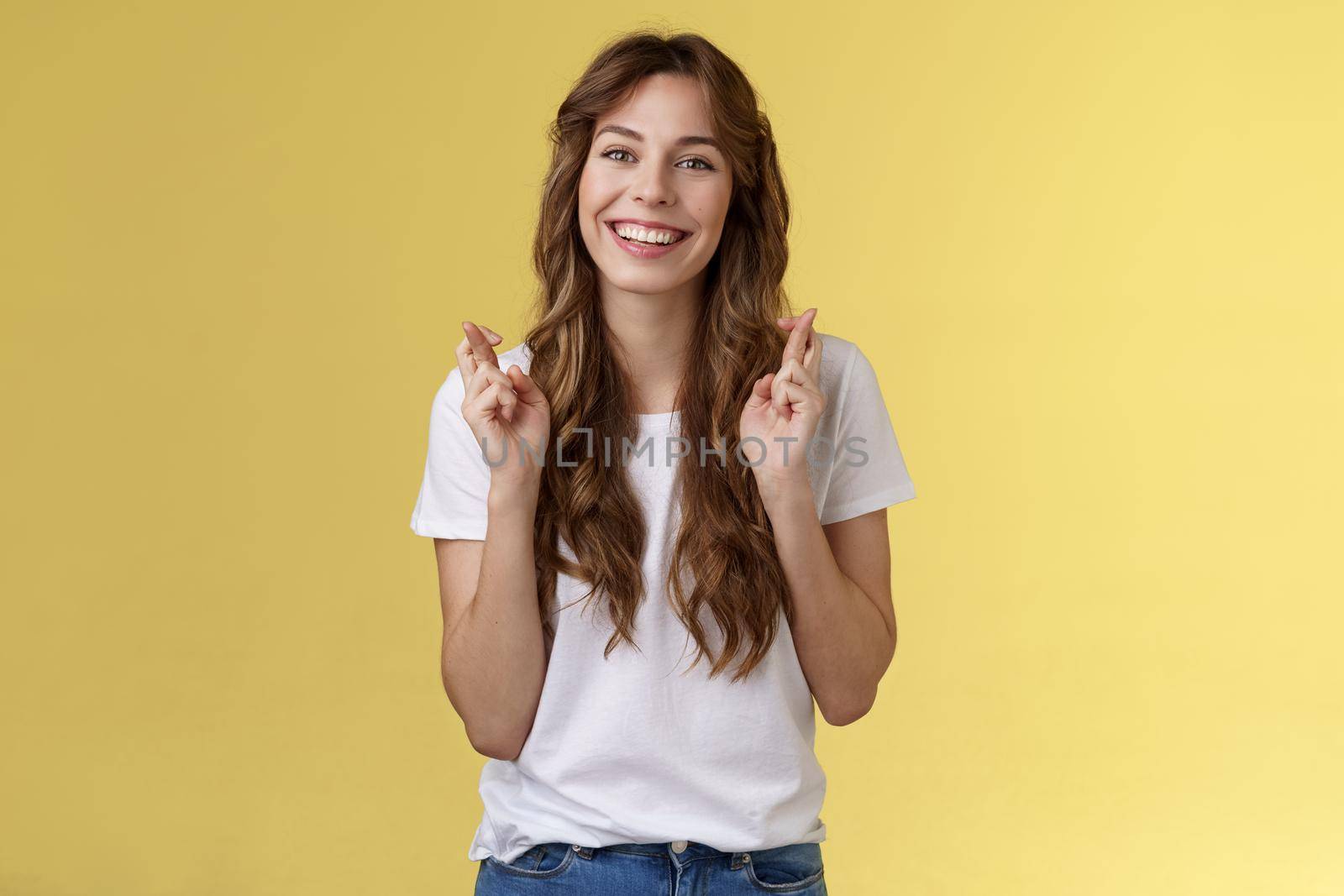 Girl faithfully believe dream come true hopefully awaiting positive results smiling broadly cross fingers good luck implore god good news stand excited optimistic yellow background by Benzoix