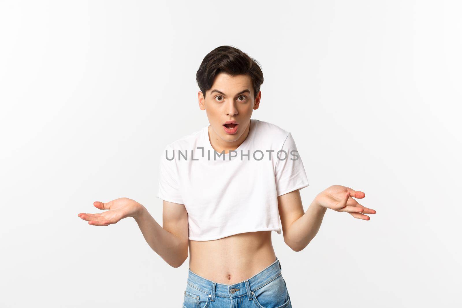 Lgbtq community. Confused gay man in crop top shrugging and staring at camera, cant understand, standing over white background.