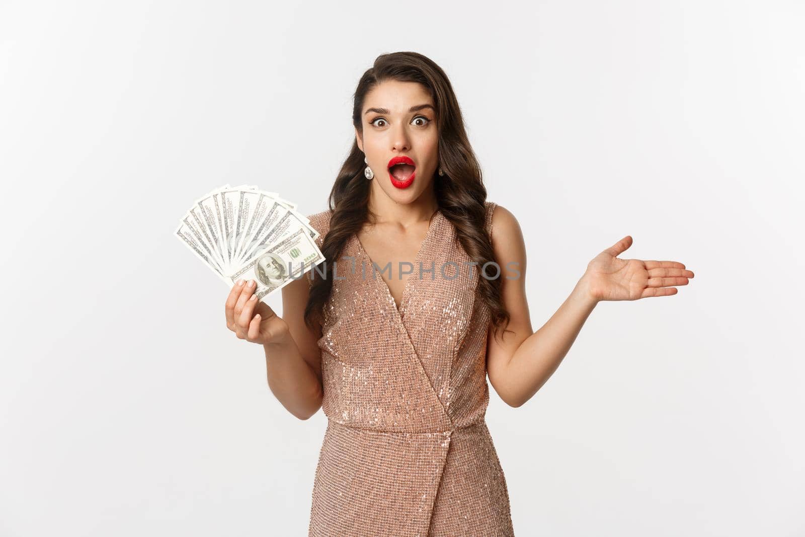 Shopping concept. Elegant woman in glamour dress holding money and looking surprised. winning prize, standing over white background.