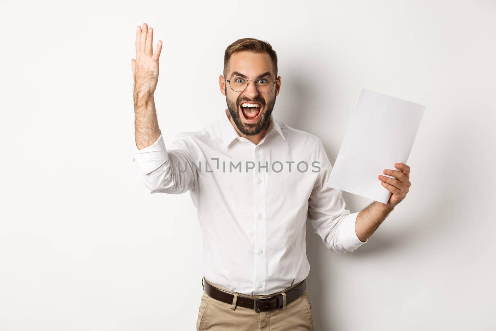Angry businessman shouting and showing bad report, looking disappointed and frustrated, standing over white background.