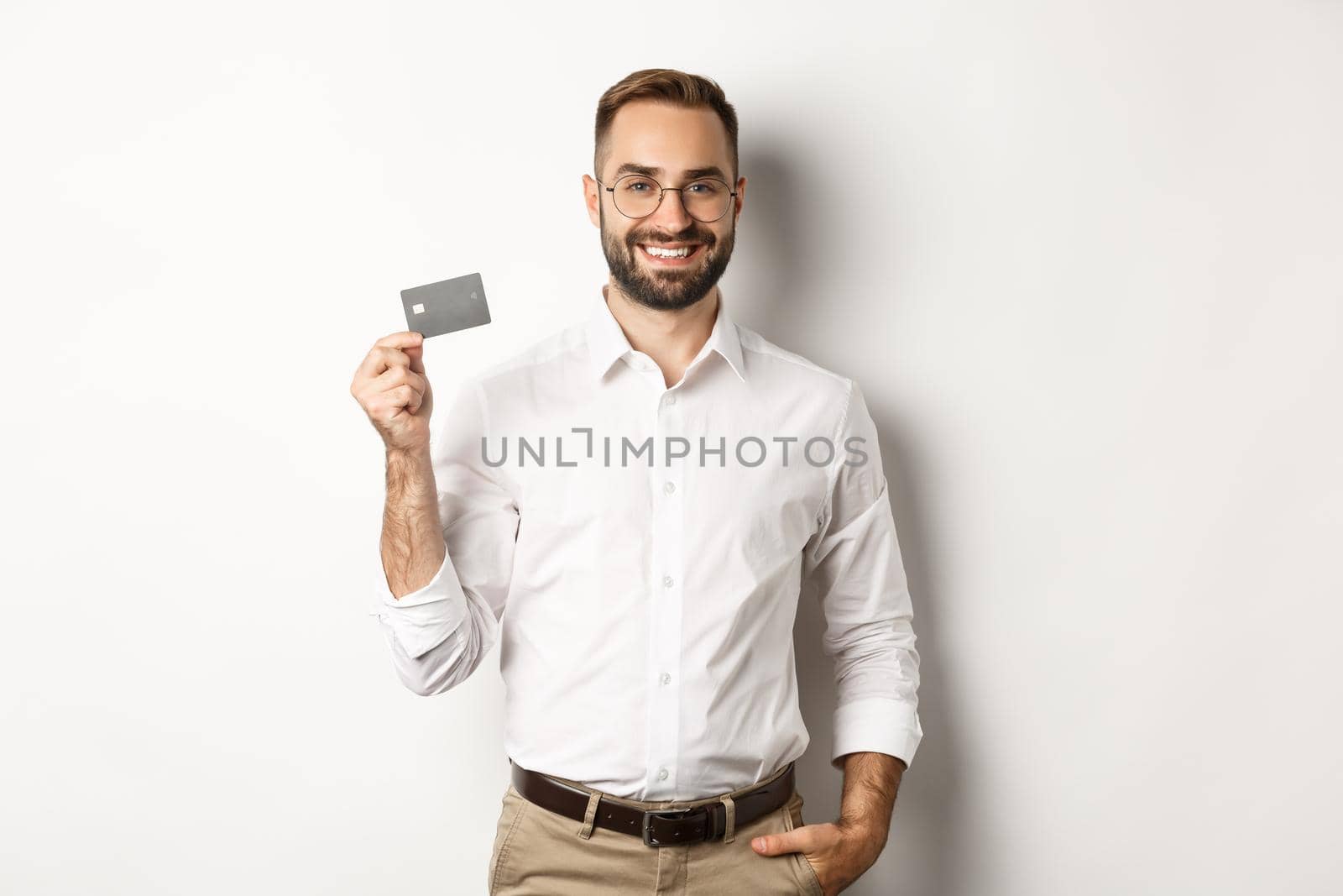 Handsome businessman showing his credit card, looking satisfied, standing over white background by Benzoix