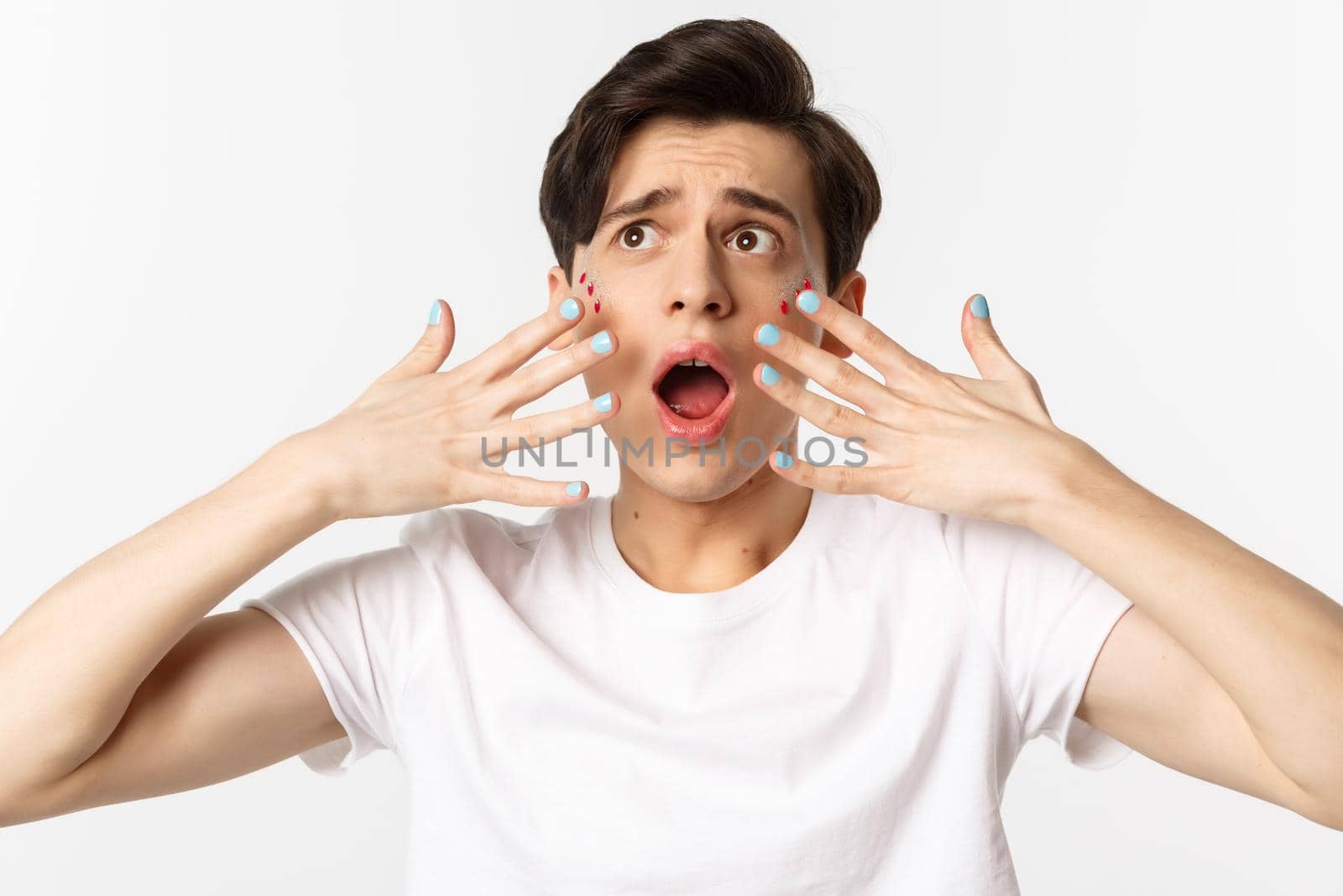People, lgbtq and beauty concept. Close-up of gay man panicking, showing nail polish on hands, looking alarmed and worried, standing over white background.