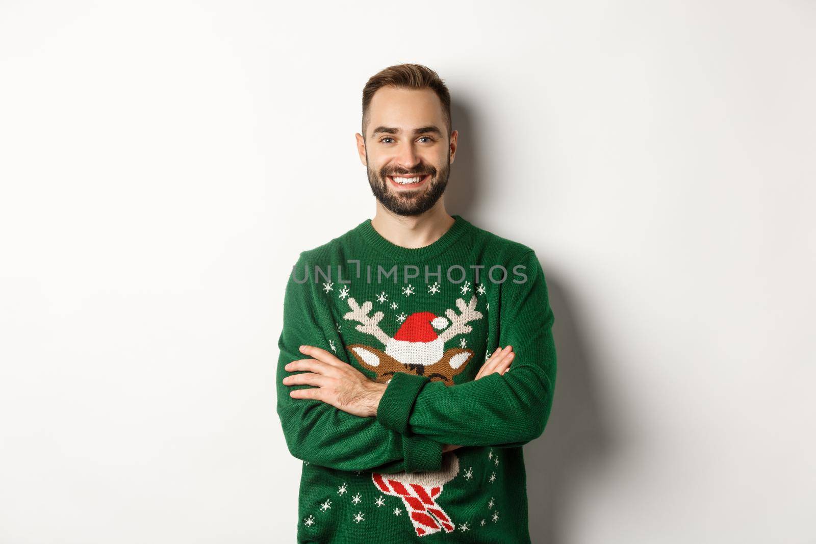 New Year party and winter holidays concept. Happy bearded man in funny christmas sweater standing against white background.