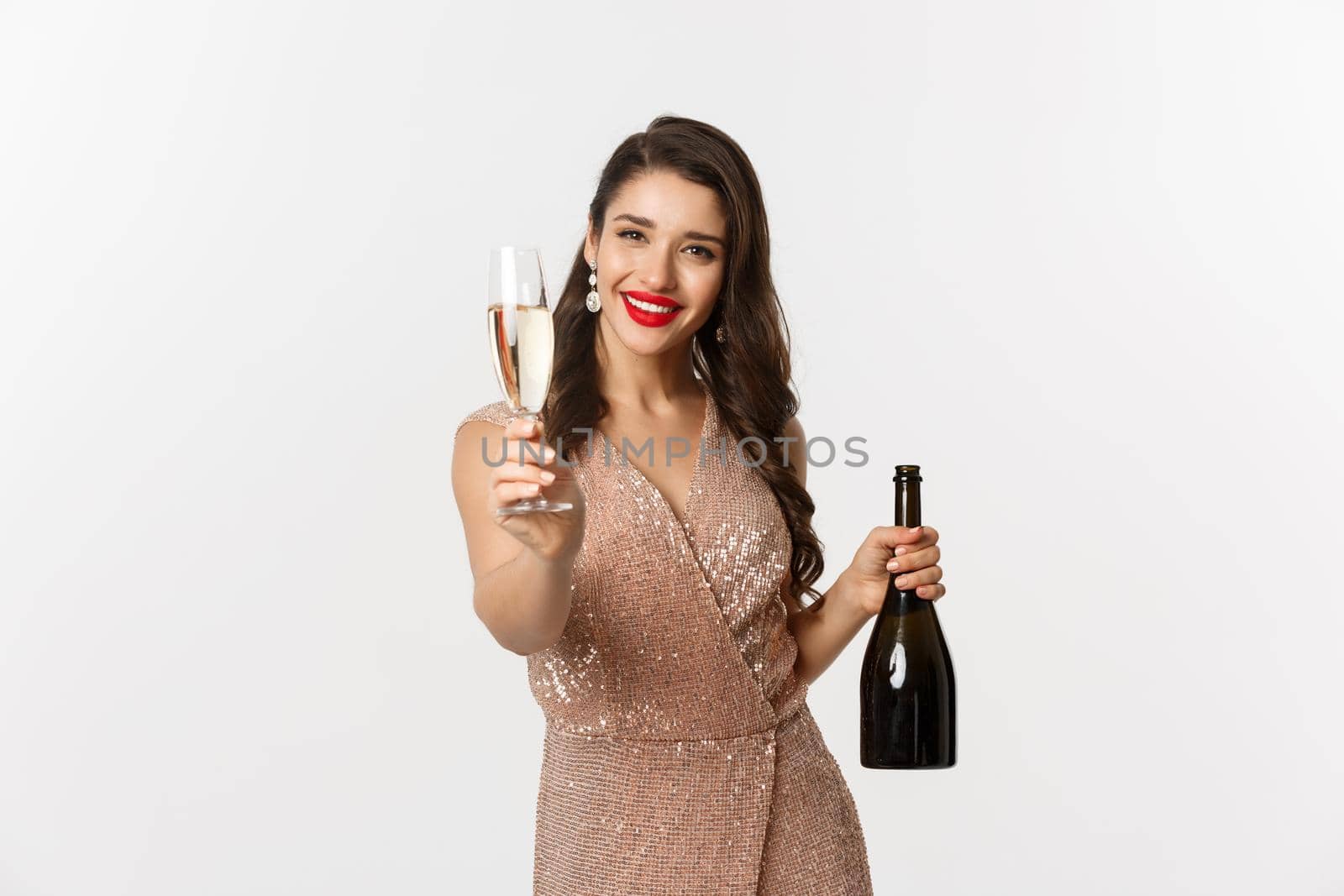 Winter holidays celebration concept. Beautiful woman in elegant dress giving you glass of champagne on Christmas party, standing over white background by Benzoix