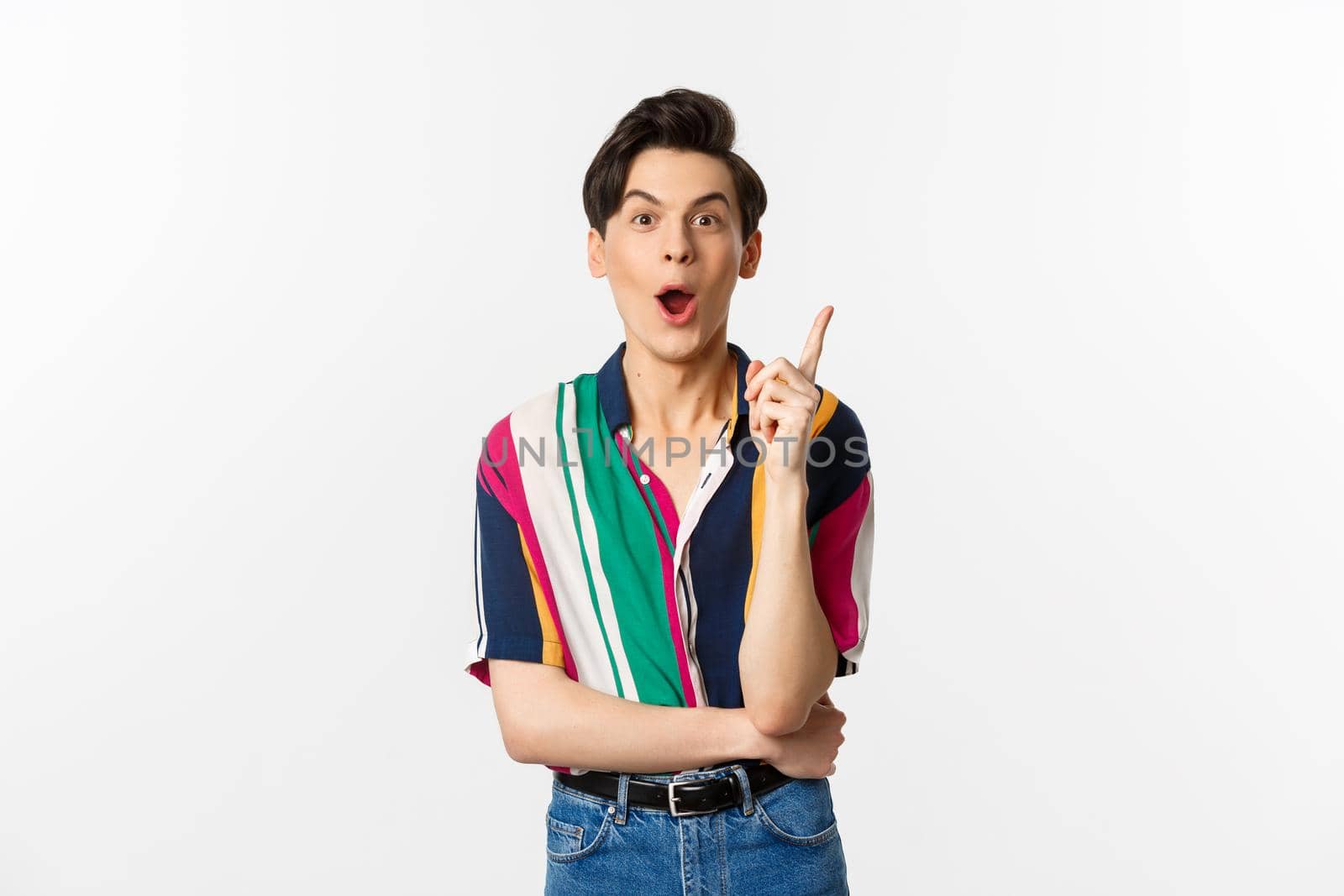 Portrait of young handsome guy having an idea, raising finger and saying suggestion, standing over white background.