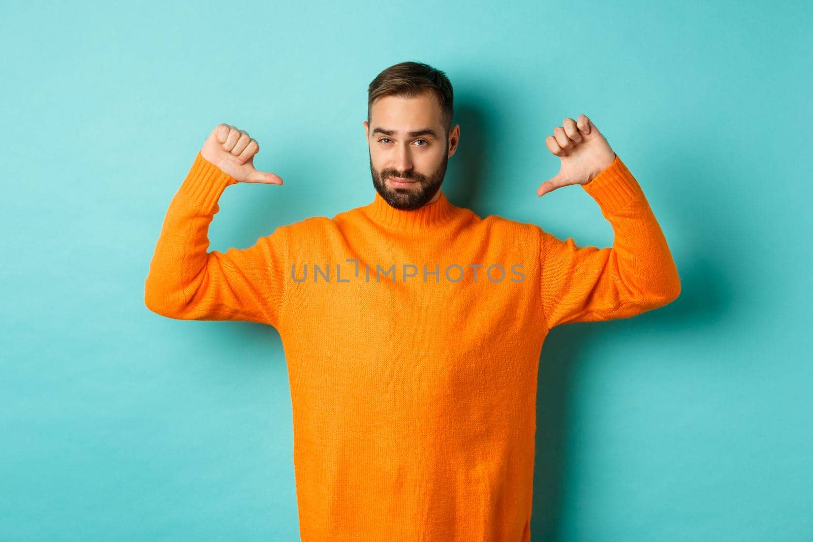 Confident attractive guy pointing at himself, show-off or brag, standing over light blue background by Benzoix