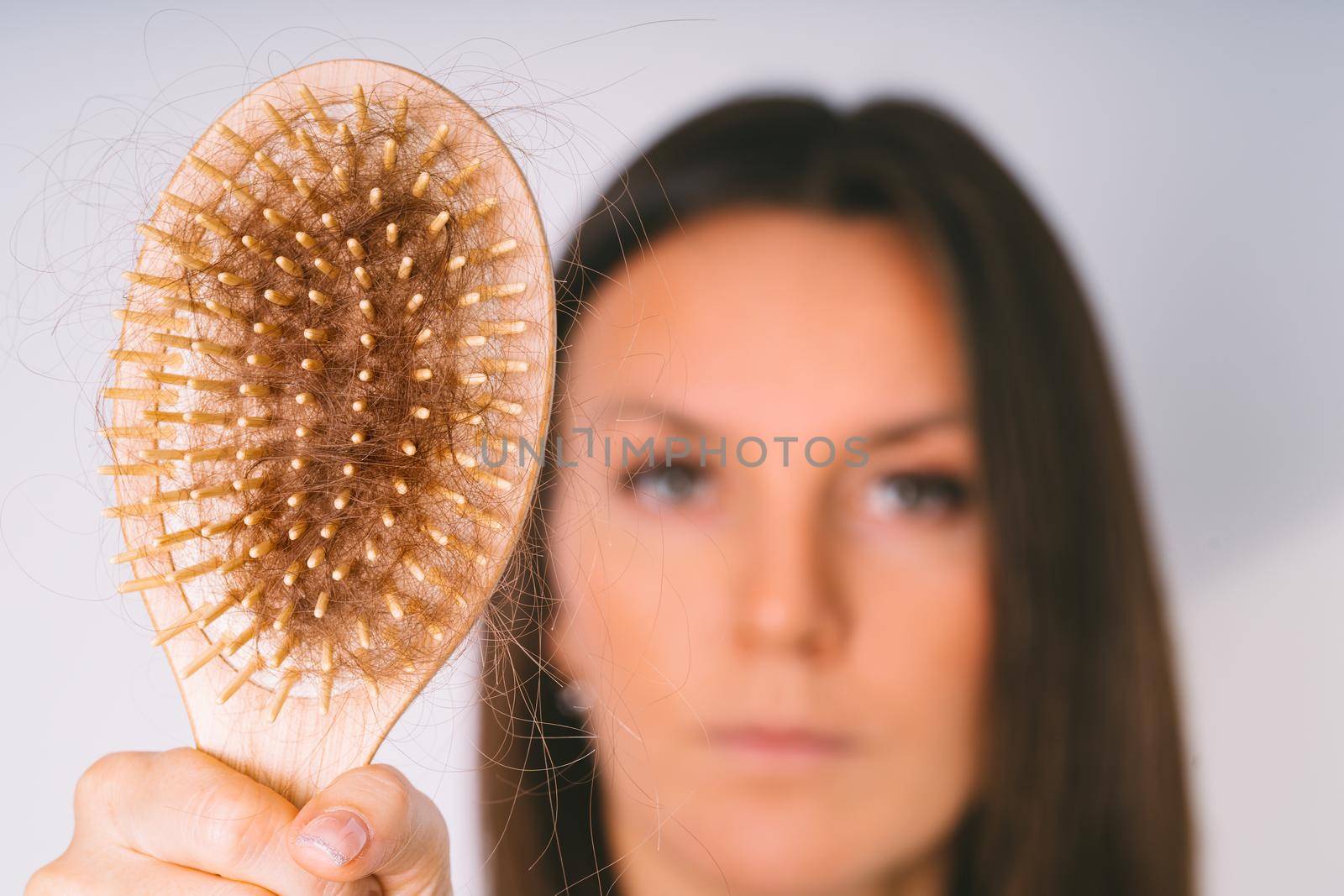 Woman showing hair brush with damaged hair. Hair loss problem. Bad hair falling out. High quality photo