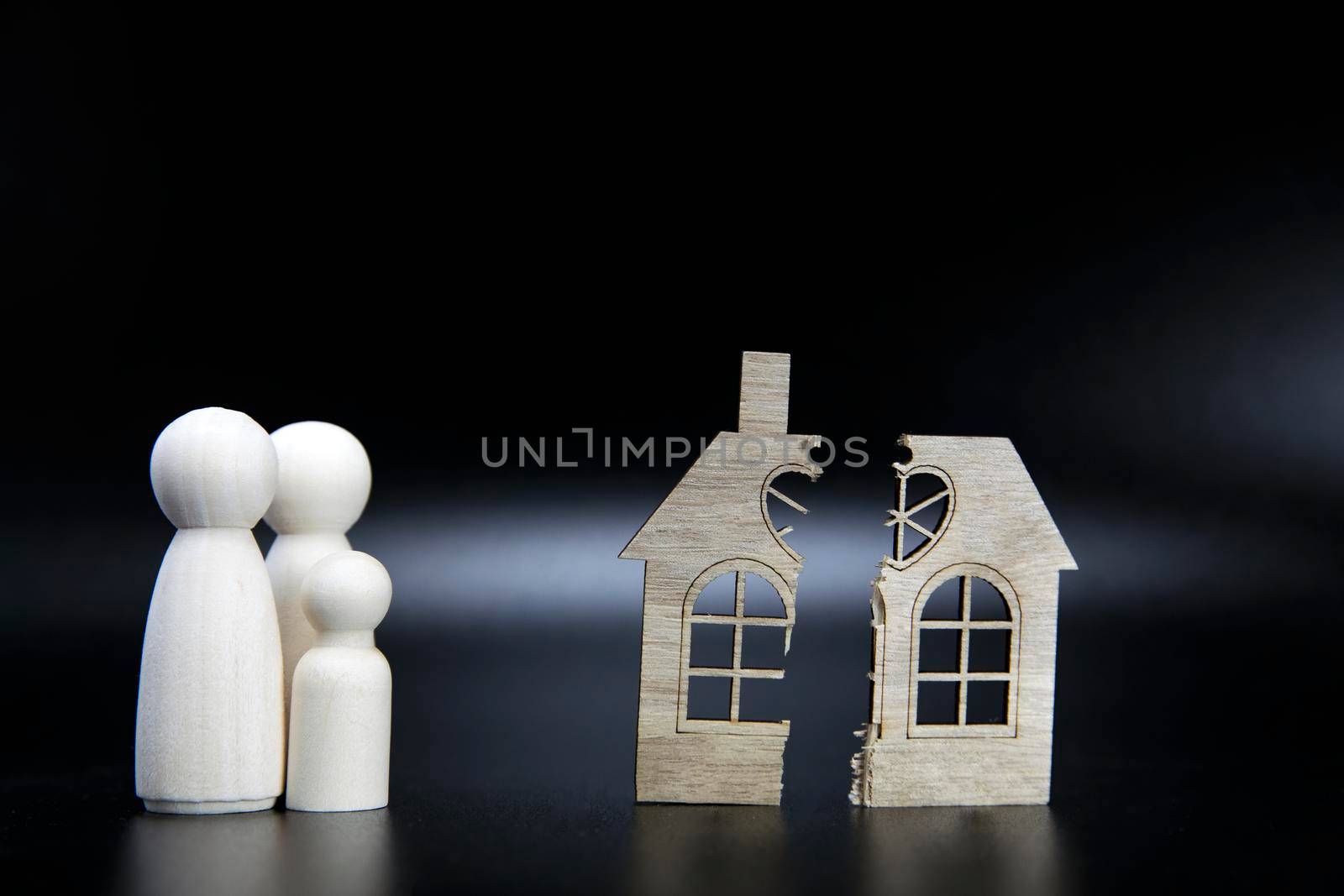 Divorce, division of property, poverty and no money concept. Wooden broken house on black background. Mortgage, rent, realtor concept copy space space for text