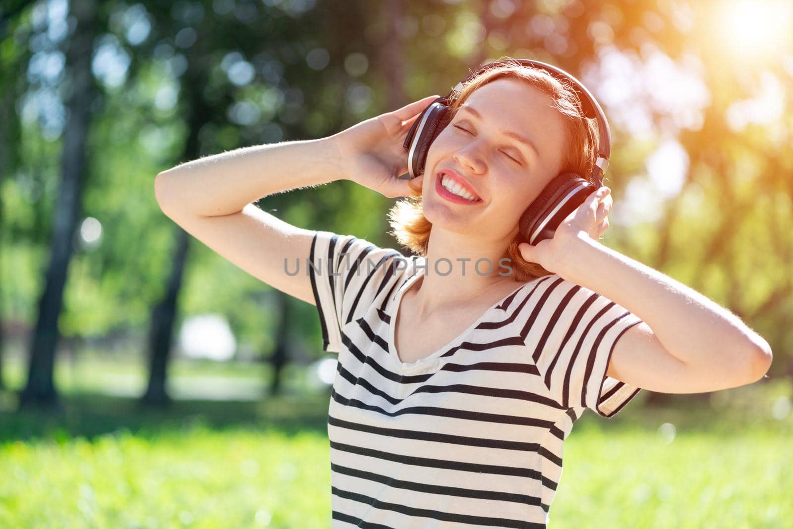 Young attractive woman listens to music in the park. Enjoying music in the park