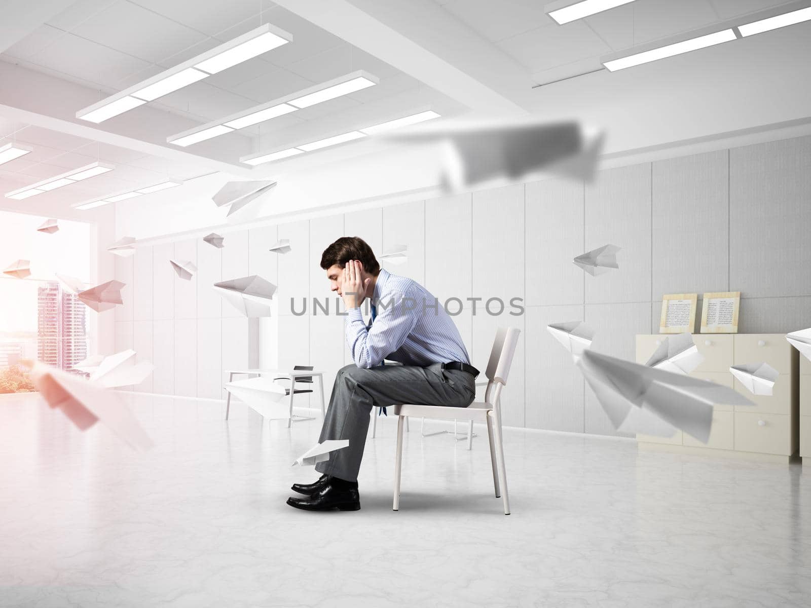 young businessman sitting on a chair with his head in his hands