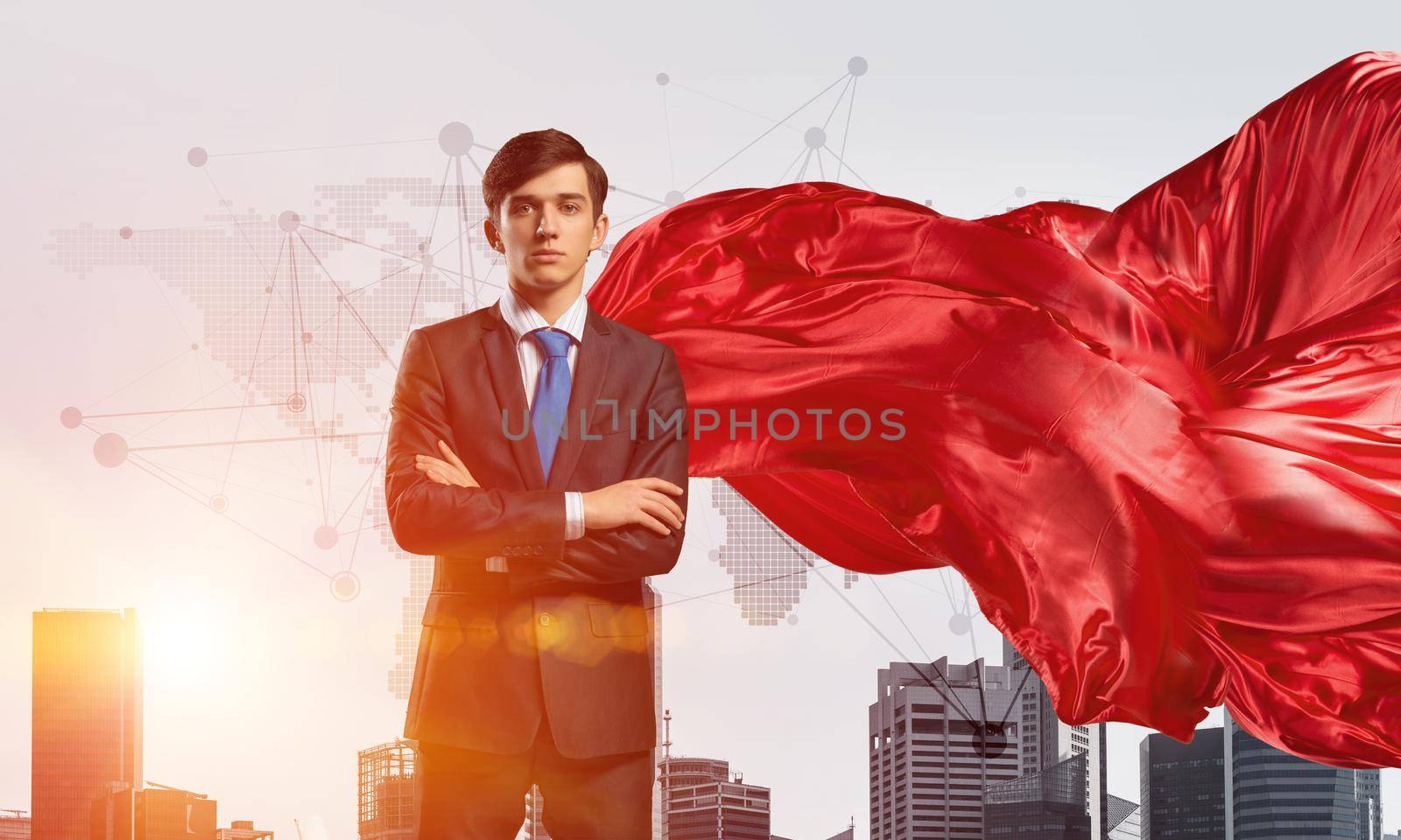 Young confident businessman wearing red cape against modern city background