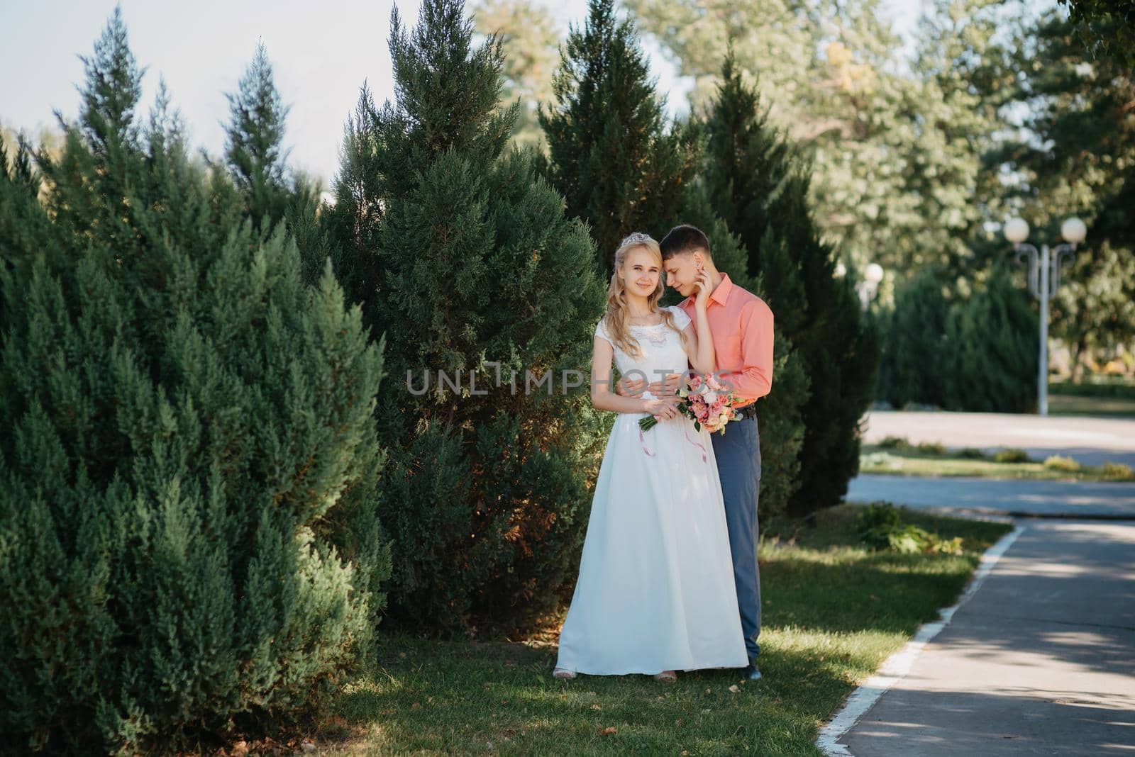 Bride and groom at wedding Day walking Outdoors on spring nature. Bridal couple, Happy Newlywed woman and man embracing in green park. Loving wedding couple outdoor. Wedding shot of bride and groom in park. Elegant bride and groom posing together outdoors on a wedding day. wedding couple in the park by Andrii_Ko