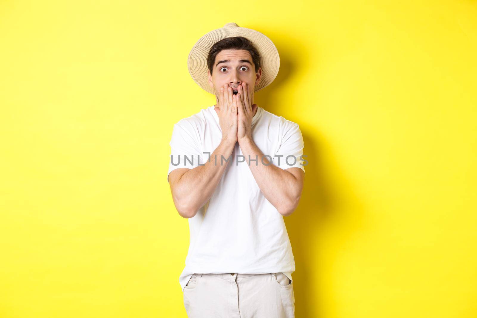 Concept of tourism and summer. Shocked guy jumping from fear, standing startled against yellow background by Benzoix