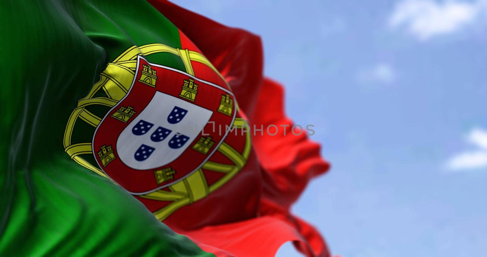 Detail of the national flag of Portugal waving in the wind on a clear day. Democracy and politics. European country. Selective focus