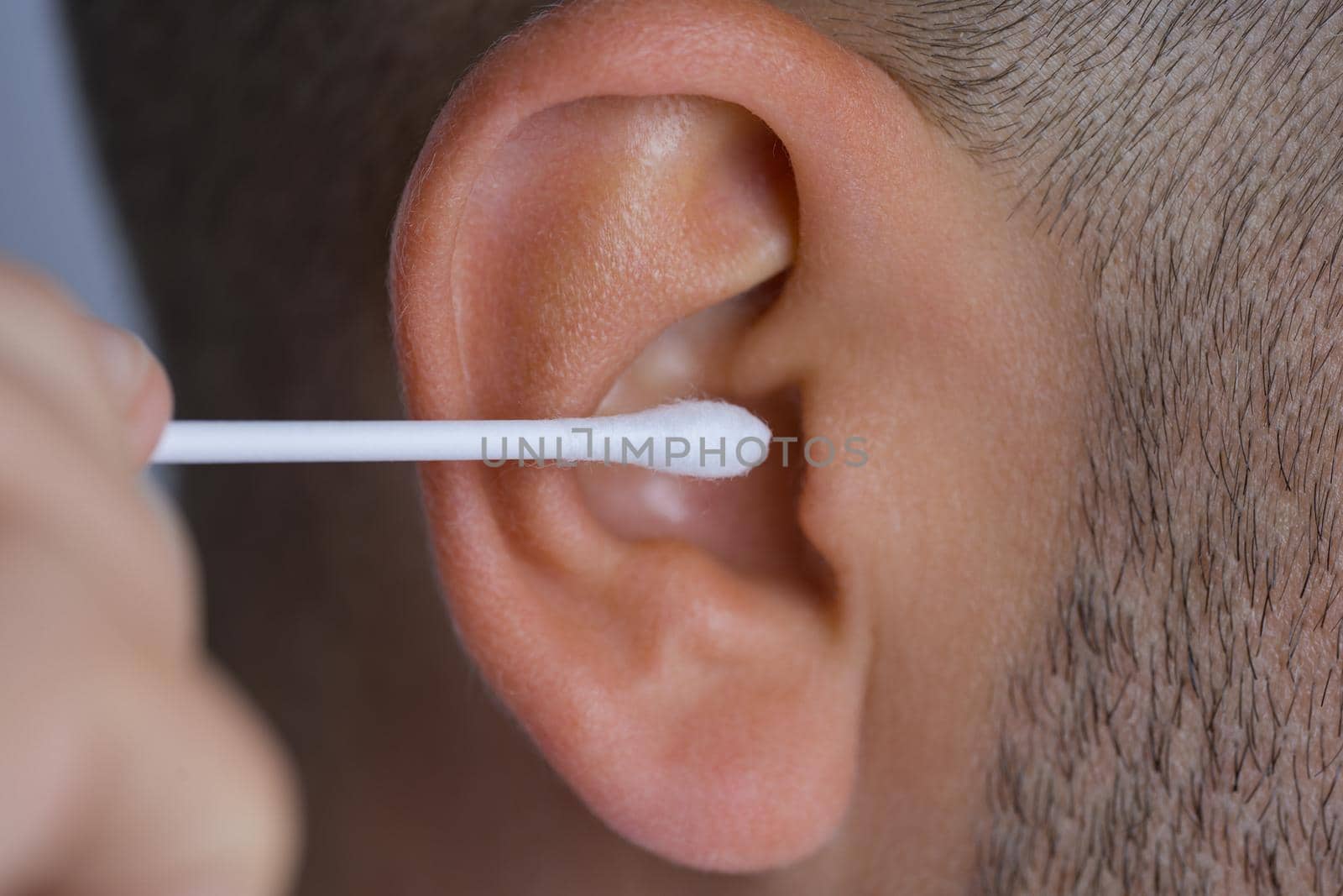 Closeup of man cleaning dirty ears with cotton swab or cotton stick. High quality photo