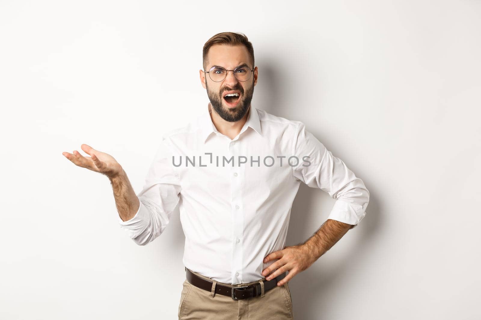 Frustrated office worker complaining, gesturing and looking disappointed, standing over white background.
