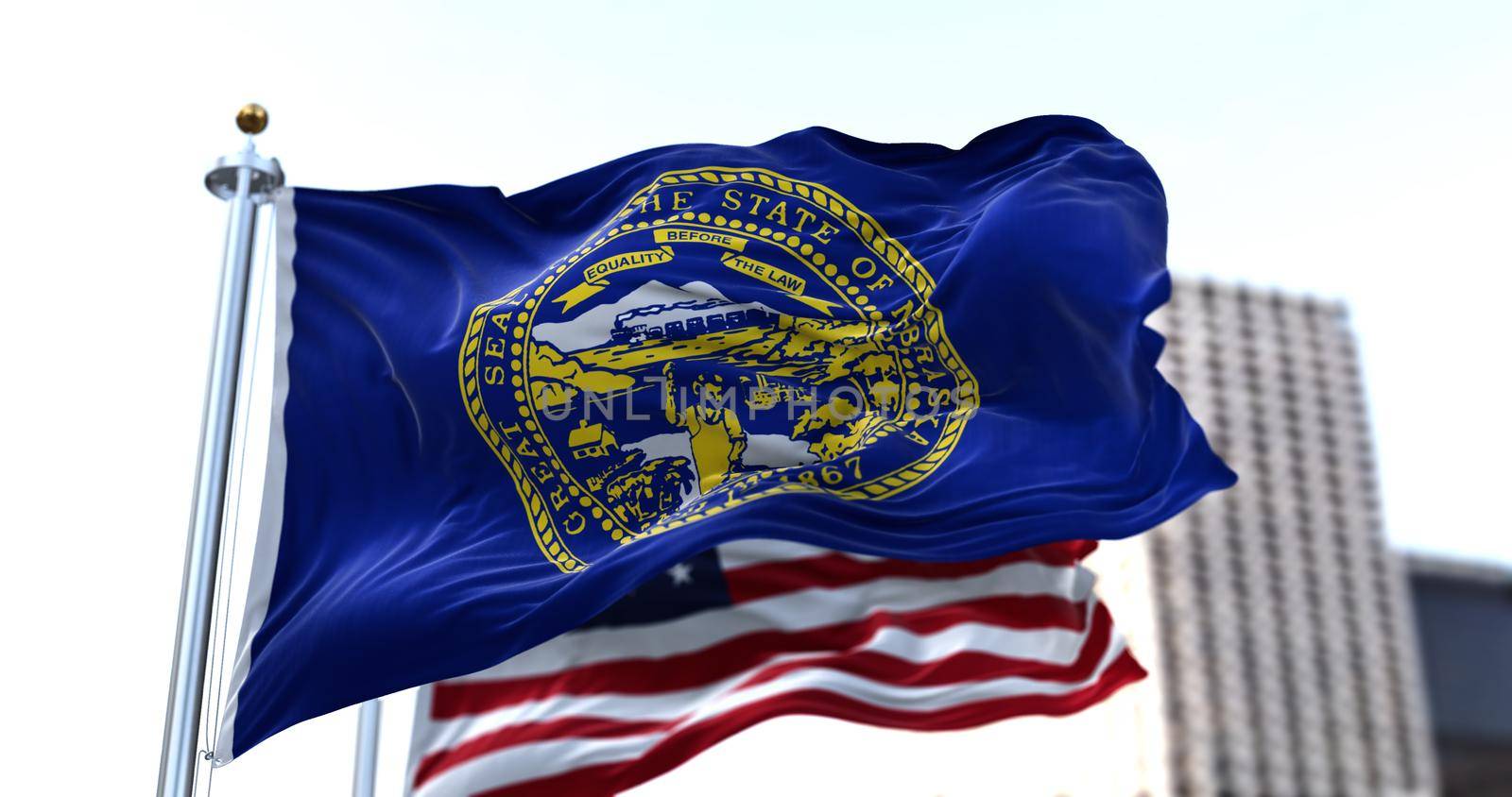 the flag of the US state of Nebraska waving in the wind with the American flag blurred in the background. Nebraska was admitted to the Union on March 1, 1867 as 37th state