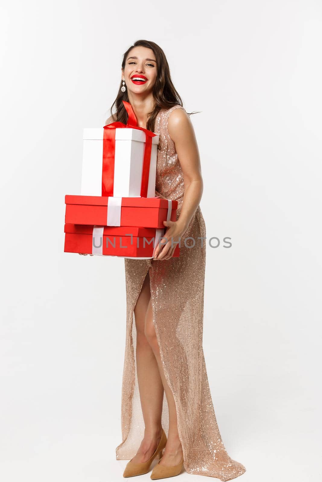 Party and celebration concept. Full-length of attractive brunette in glamour dress, holding Christmas gifts and laughing happy, white background.