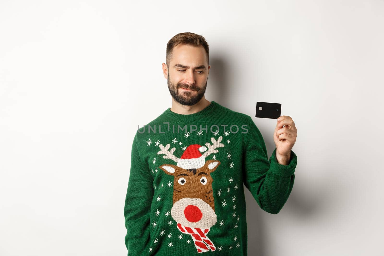 Christmas holidays and shopping concept. Thoughtful man looking at credit card, thinking and standing over white background.