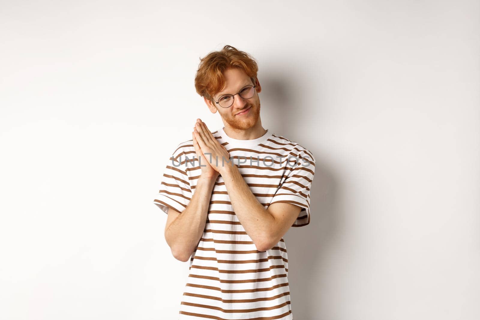 Cunning redhead man having plan, rubbing palms and looking devious at camera, smirk and squint sly, standing over white background.