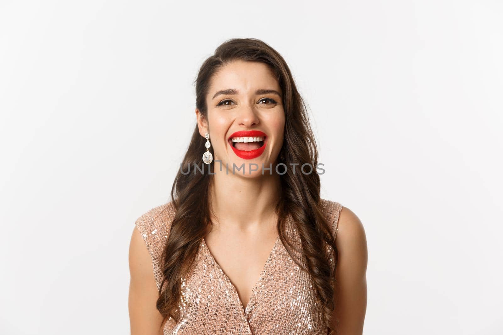 Concept of New Year celebration and winter holidays. Close-up of happy young woman dressed for party, laughing and smiling at camera, white background.