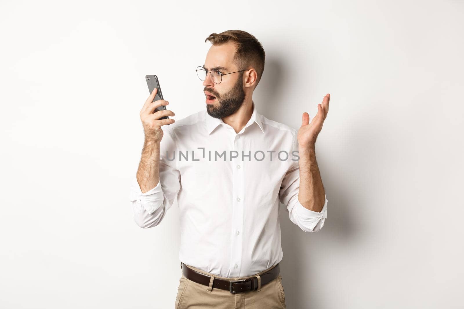 Man looking confused at mobile phone after conversation, standing puzzled over white background by Benzoix