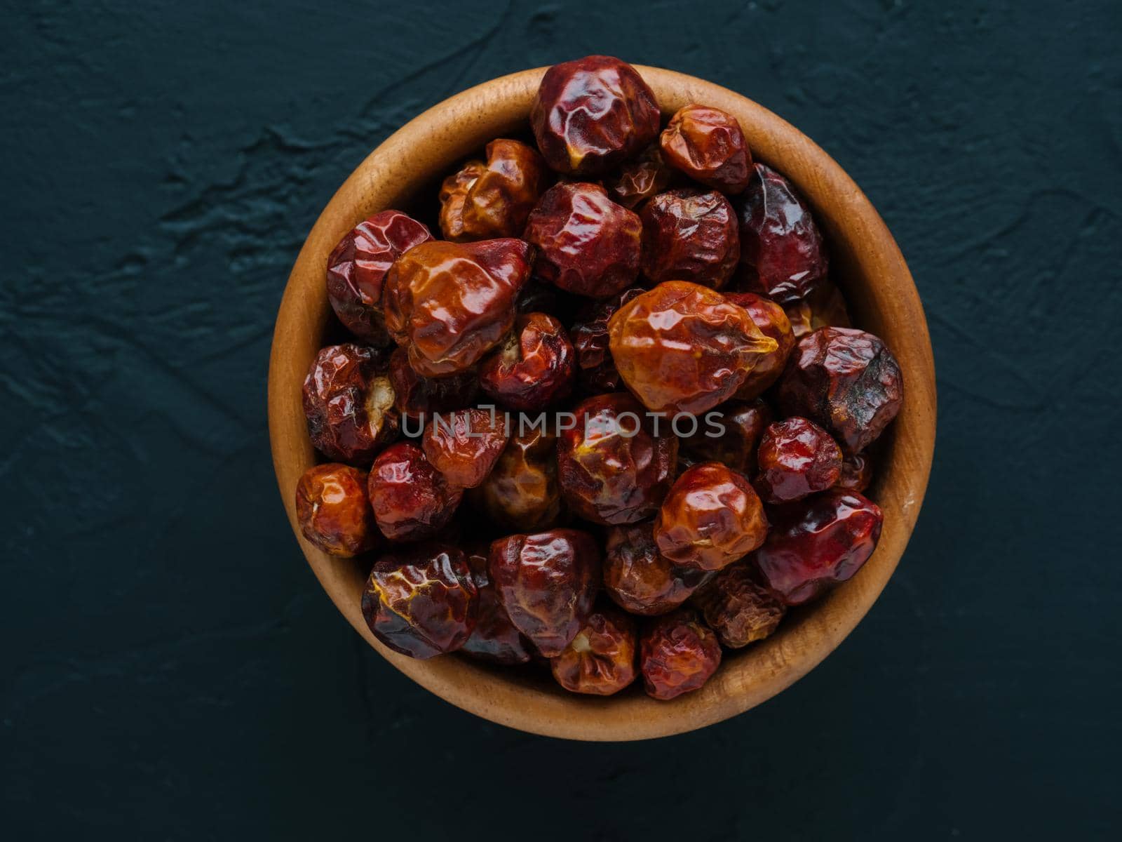 Dried fruits of Capsicum frutescens, used as hot spice and for tabasco sauce. Whole small dry red hot pepper on bowl in black stone background. Spices and seasonings for cooking. Top view. Soft focus