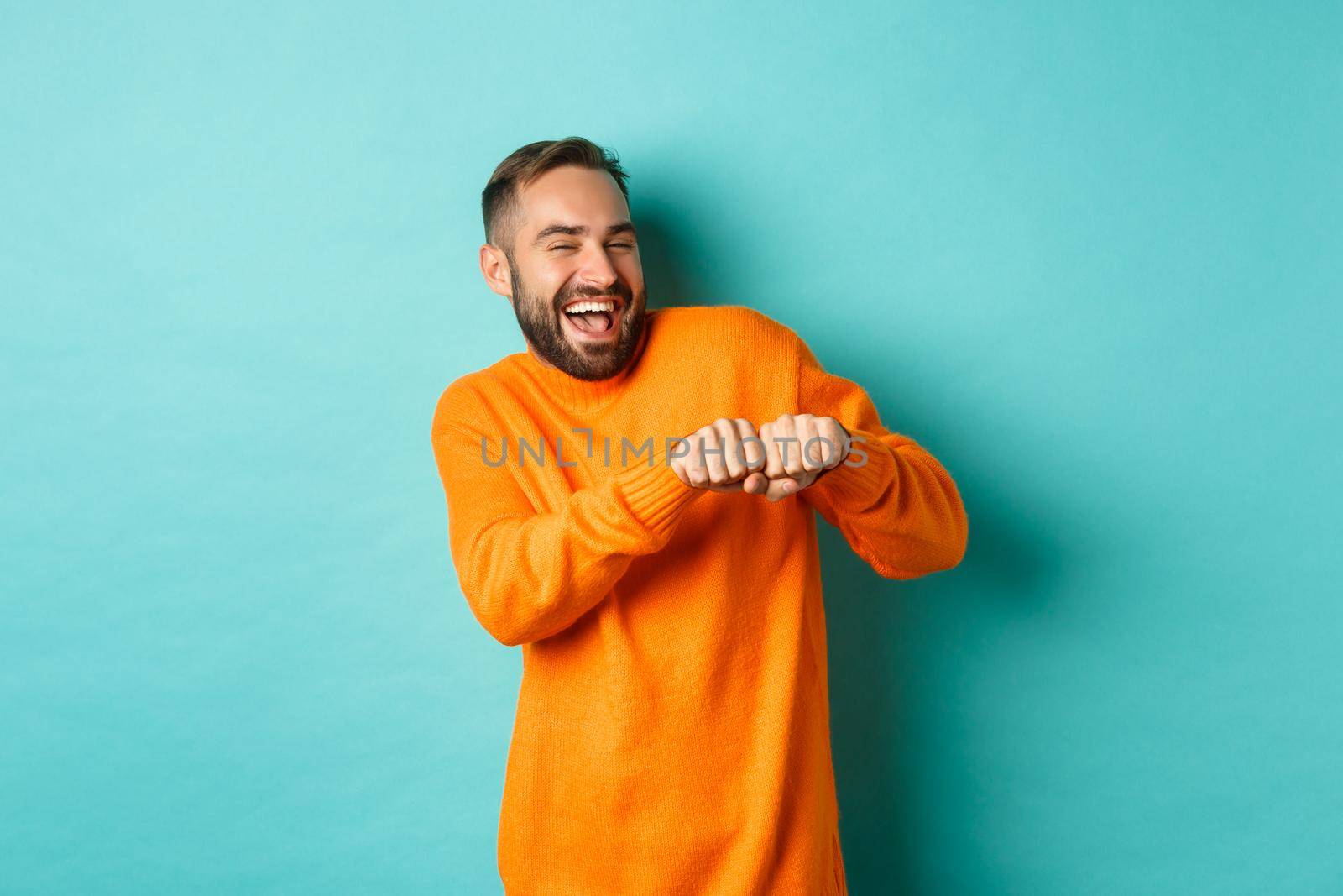 Happy man dancing and celebrating success, feeling like winner, smiling and rejoicing, light blue background.