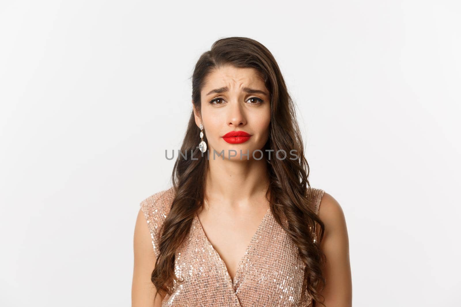 Concept of New Year celebration and winter holidays. Close-up of sad and gloomy woman with hairstyle and red lips, frowning and looking with pity, standing over white background.