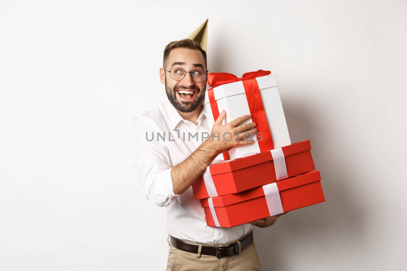 Holidays and celebration. Excited man having birthday party and receiving gifts, looking happy, standing over white background.