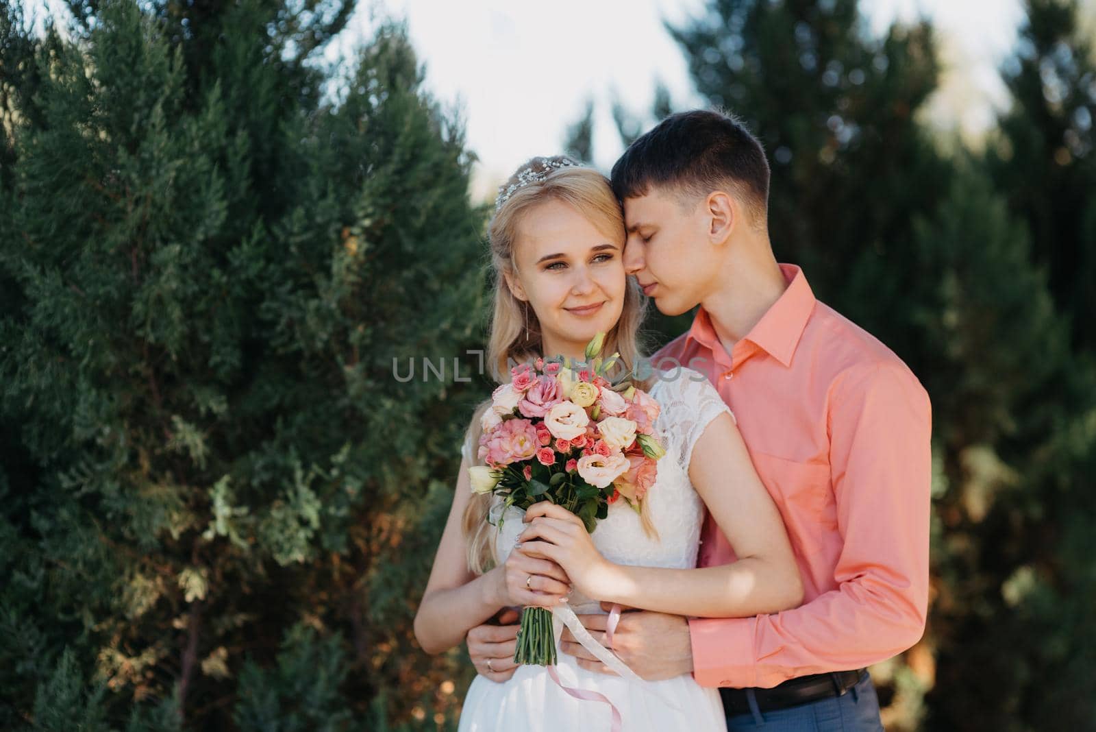 Bride and groom at wedding Day walking Outdoors on spring nature. Bridal couple, Happy Newlywed woman and man embracing in green park. Loving wedding couple outdoor. Wedding shot of bride and groom in park. Elegant bride and groom posing together outdoors on a wedding day. wedding couple in the park by Andrii_Ko