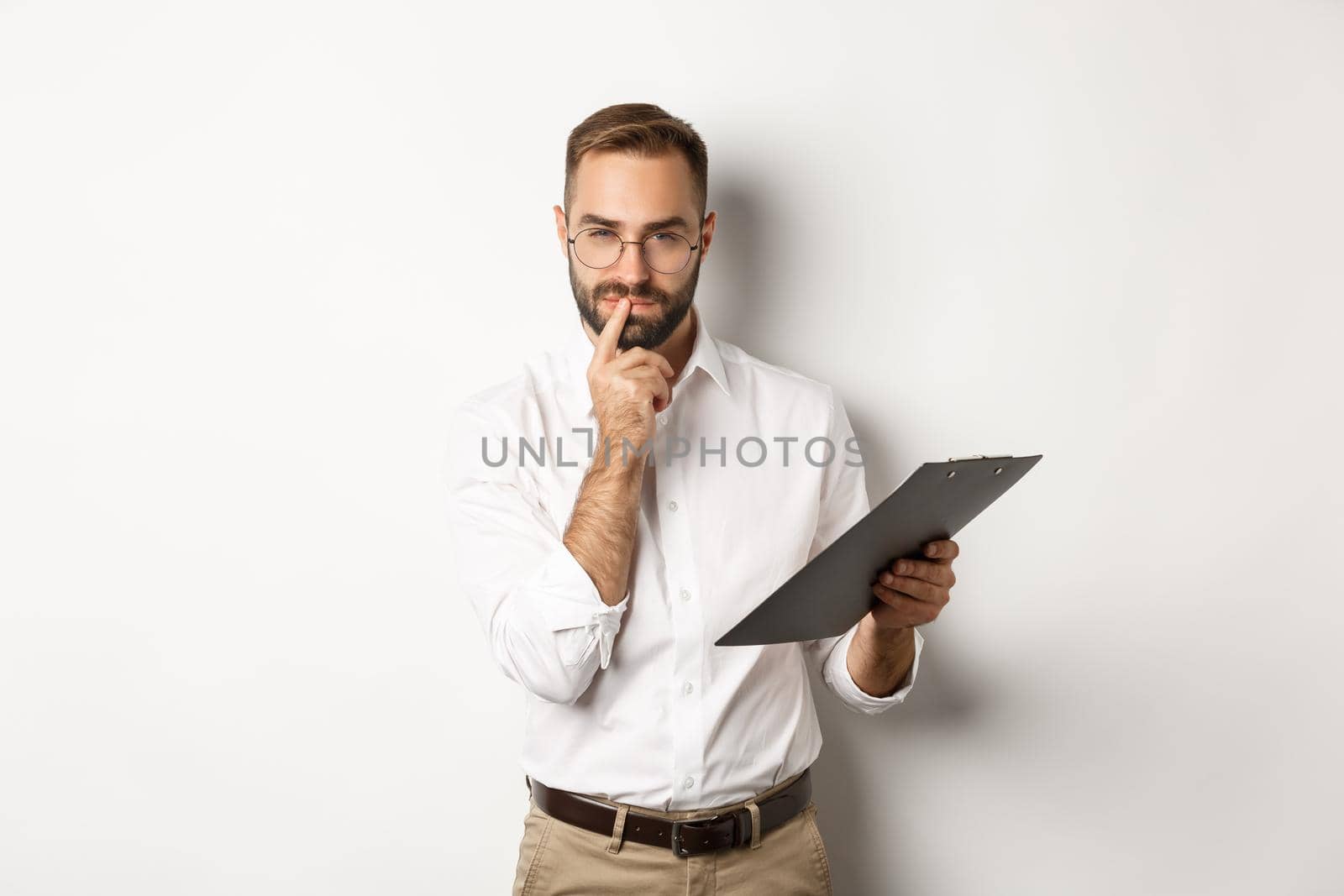 Thoughtful office employee working, holding documents on clipboard and thinking, standing over white background by Benzoix