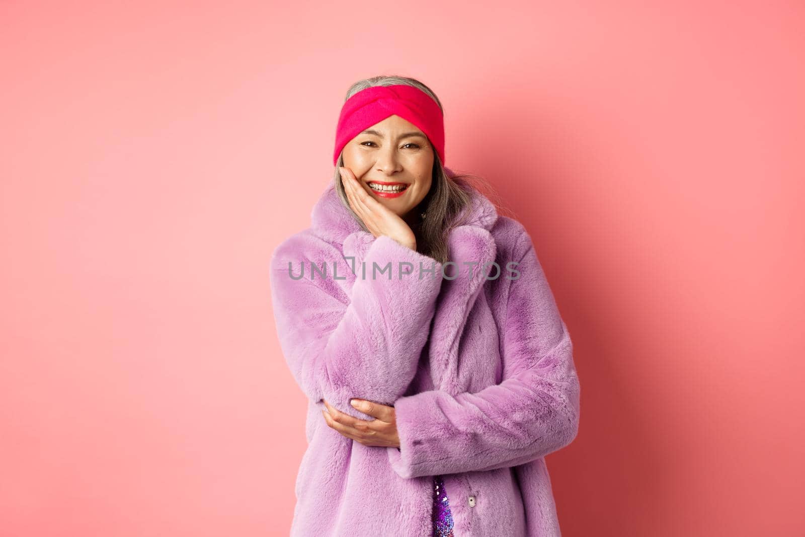 Fashion and shopping. Beautiful and romantic asian mature woman looking caring and heartfelt at camera, smiling happy, standing over pink background by Benzoix
