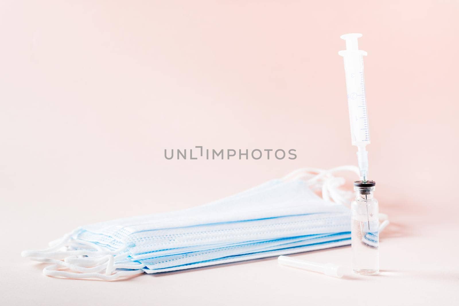 Vaccination and Immunization. Syringe needle inserted into glass vaccine vial and face mask by Aleruana