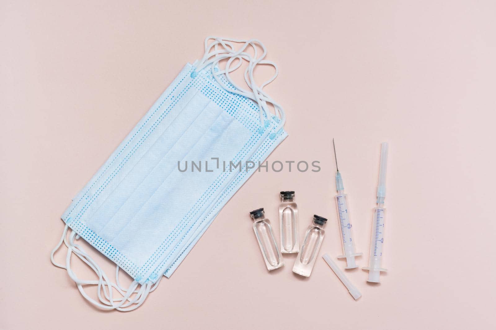 Vaccination and Immunization. Clean syringes, glass vial with vaccine and face protective masks. Top view. Close-up