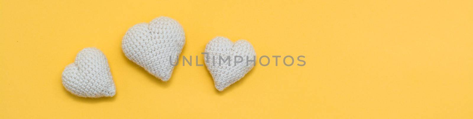 Handmade for Valentine's Day. Knitted white hearts on a yellow background. Web banner by Aleruana