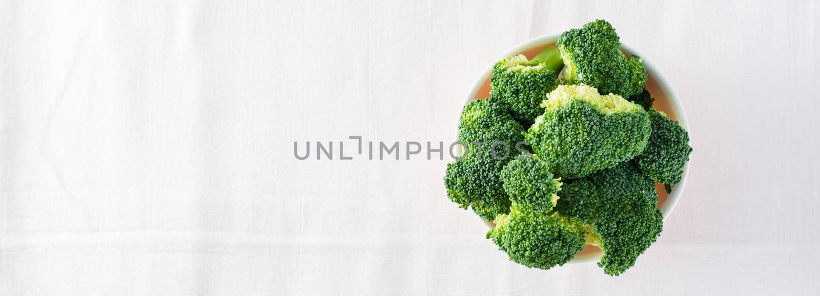 Fresh broccoli in a bowl on a table on a cloth. Diet healthy food. Top view. Copy space. Web banner