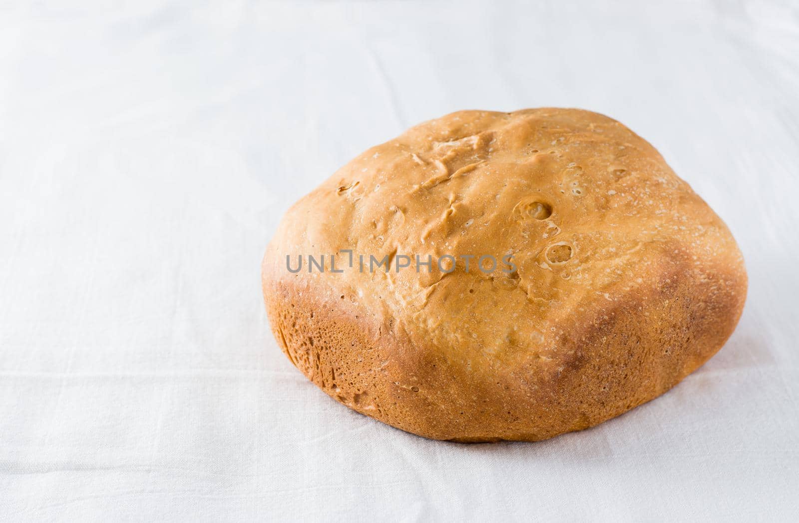 Fresh loaf of wheat homemade bread on white cloth. Copy space