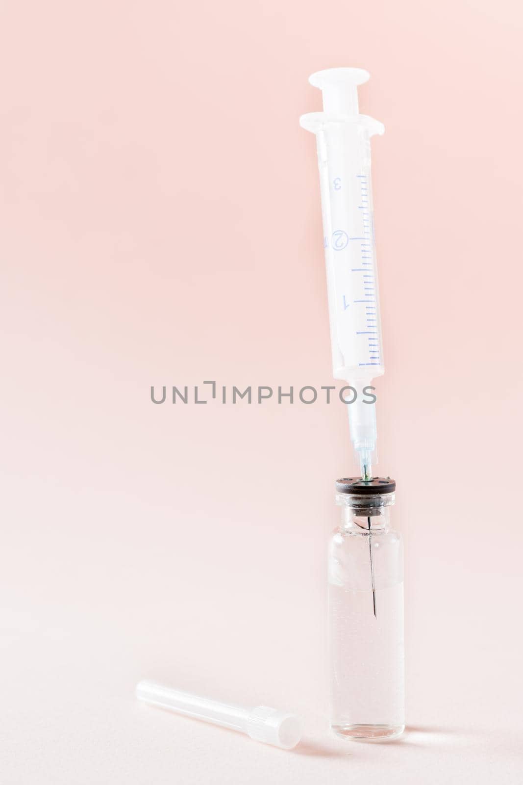 Vaccination and Immunization. Syringe needle inserted into a glass vial with vaccine. Vertical view by Aleruana