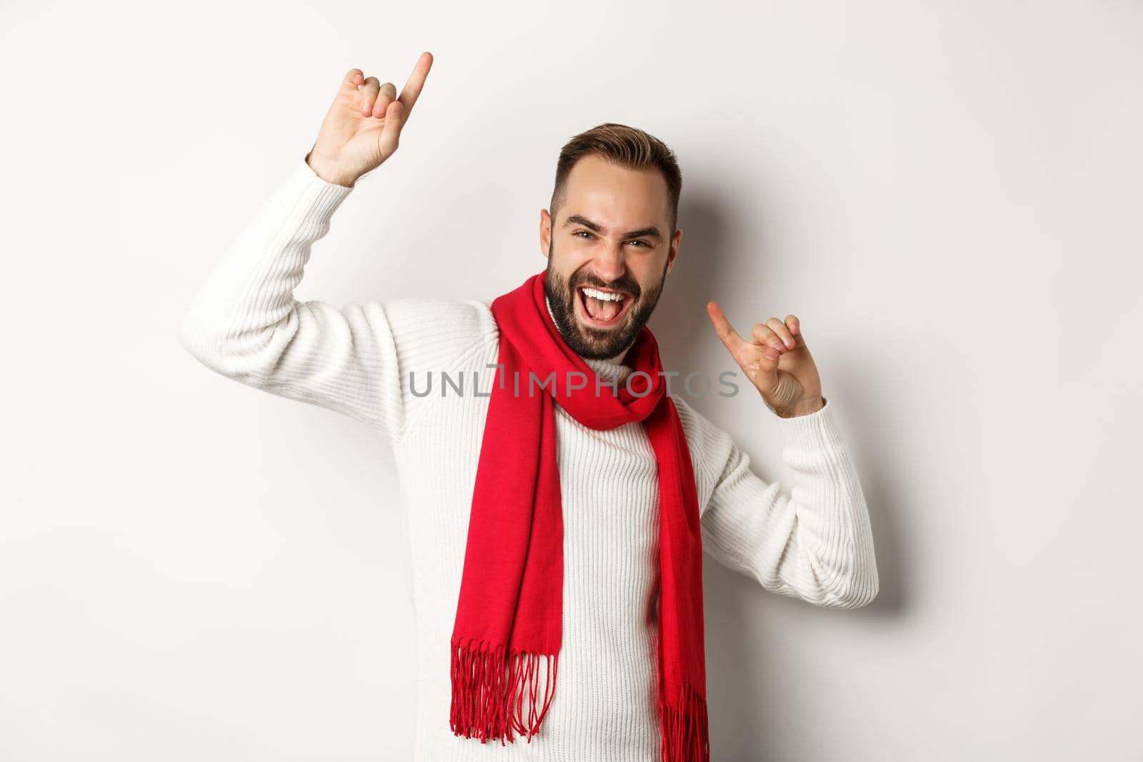 Happy bearded man celebrating new year party, dancing and pointing fingers, standing over white background.